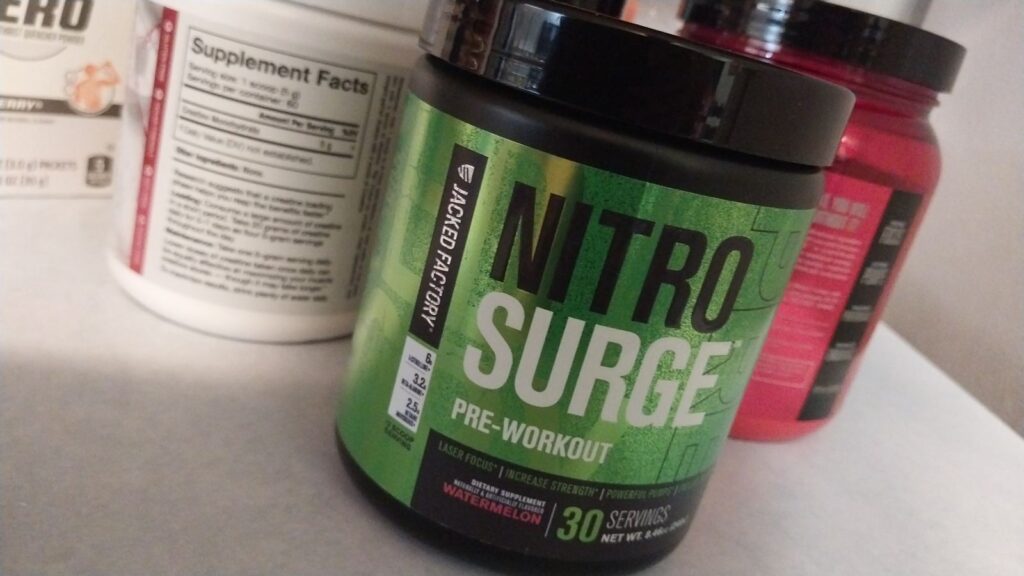 My green tub of Jacked Factory Nitrosurge Pre-workout on my kitchen counter next to my creatine supplement