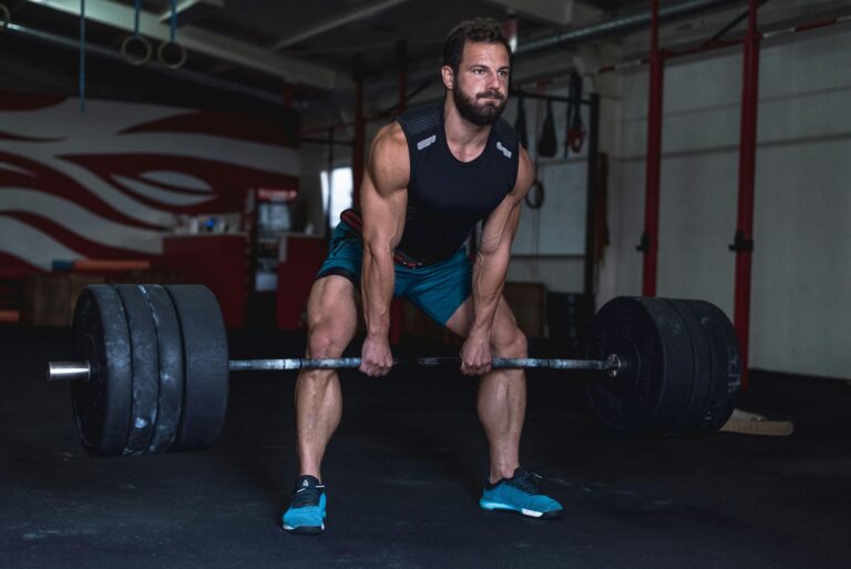 Muscular man lifting heavy barbell at a gym showcasing strength and fitness.